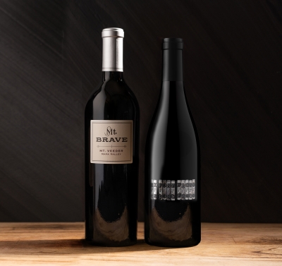 Two bottles of wine next to each other against a dark background