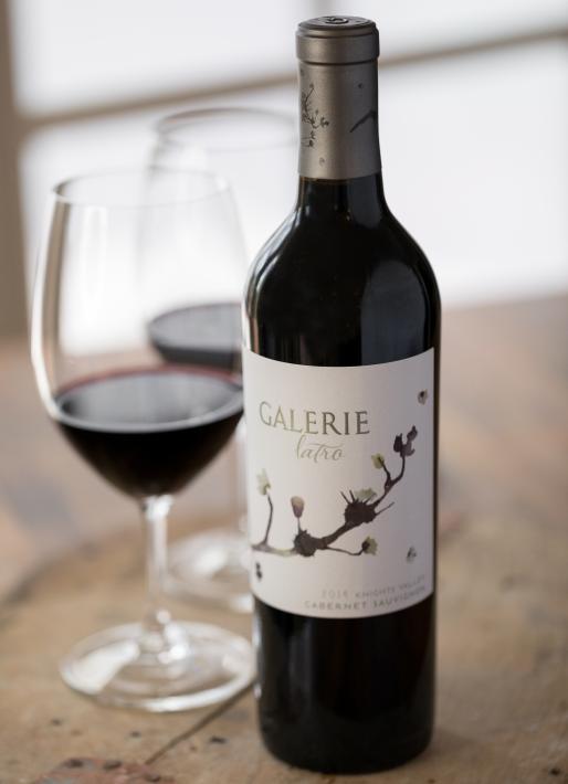 Red wine bottle with a glass of wine in the background on the left