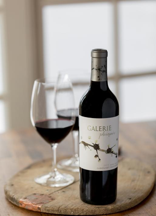 Bottle of red wine with a wine glass the left with a light background