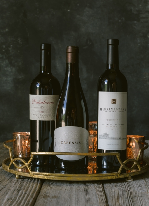 Three bottles of wine against a dark background on a serving tray