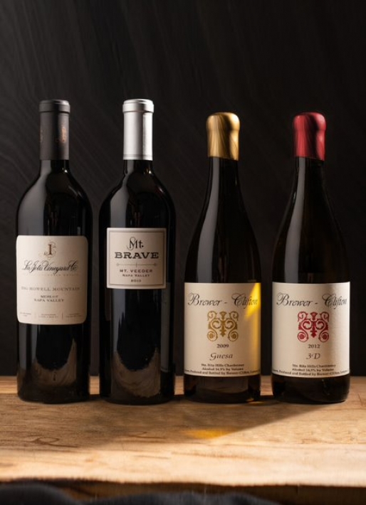 4 bottles of wine lined up against a dark background