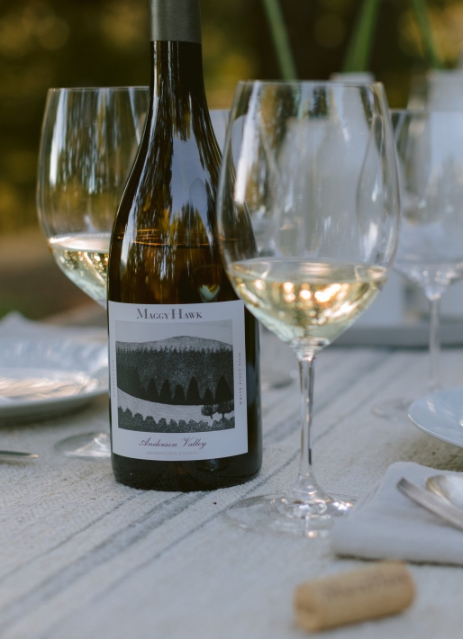Single bottle of white wine on a table with multiple wine glasses laid out