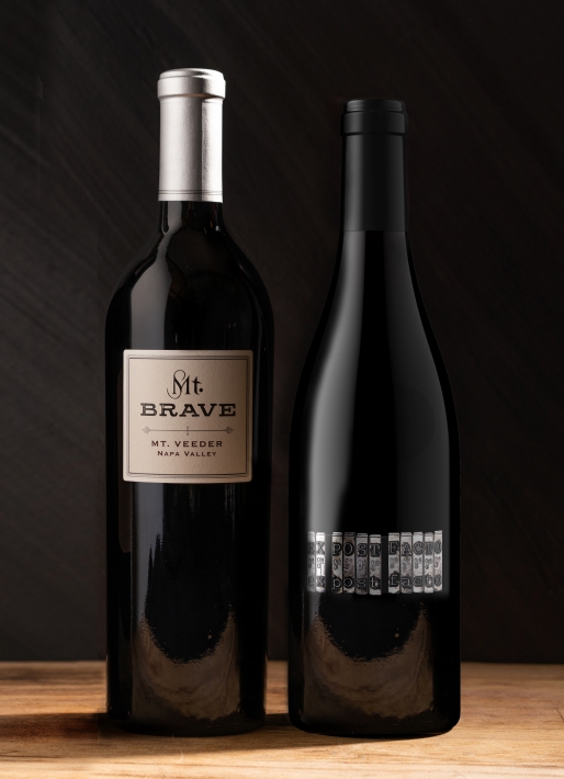 Two bottles of wine next to each other against a dark background